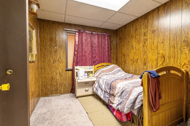 carpeted bedroom featuring wooden walls and a paneled ceiling