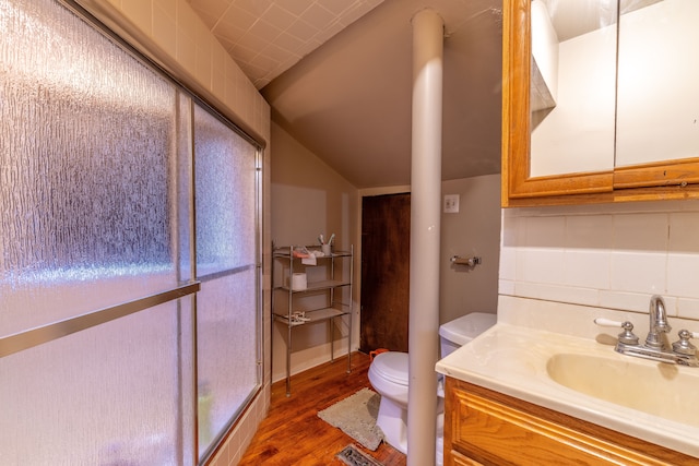 bathroom with toilet, hardwood / wood-style flooring, vanity, and lofted ceiling