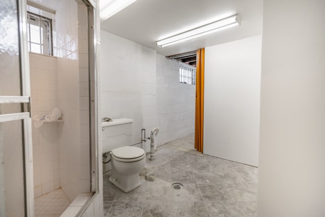 bathroom with a tile shower, toilet, and a wealth of natural light