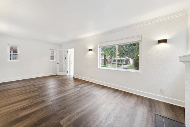 unfurnished living room featuring dark hardwood / wood-style floors, ornamental molding, and a brick fireplace