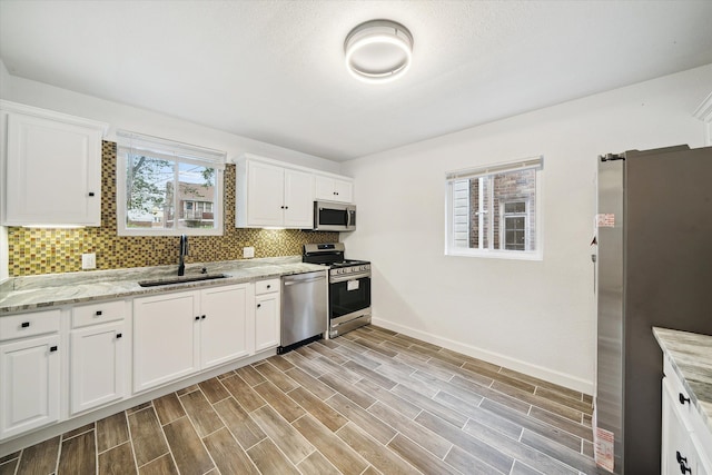 kitchen featuring light stone countertops, sink, white cabinetry, and stainless steel appliances