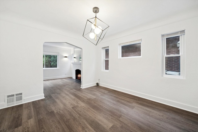 unfurnished living room with a chandelier and dark hardwood / wood-style floors