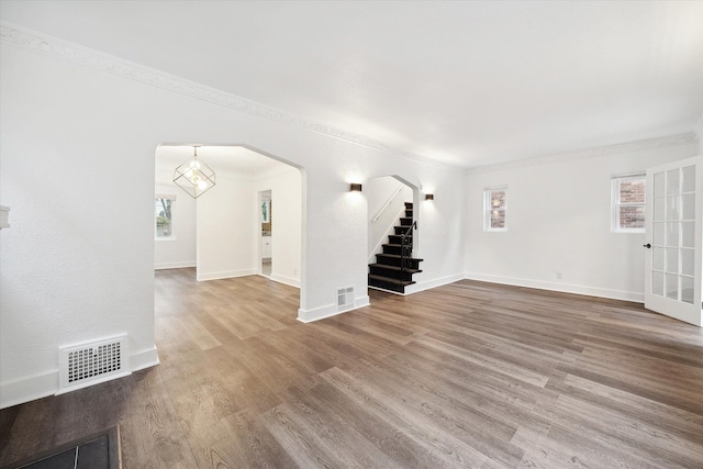 unfurnished living room with wood-type flooring, plenty of natural light, and crown molding