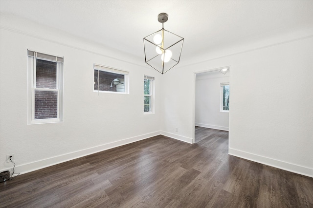 unfurnished dining area with a healthy amount of sunlight, dark hardwood / wood-style floors, and an inviting chandelier