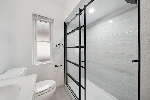 bathroom with a tile shower, vanity, and toilet