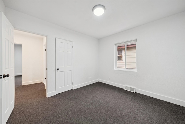 spare room featuring dark colored carpet