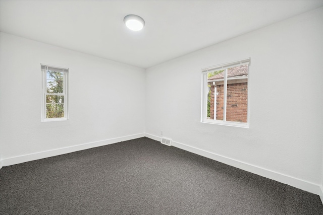 unfurnished room featuring plenty of natural light and carpet