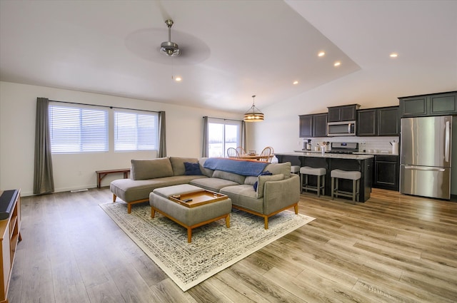 living room featuring lofted ceiling, ceiling fan, and light wood-type flooring