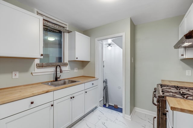 kitchen featuring white cabinets, wooden counters, and sink