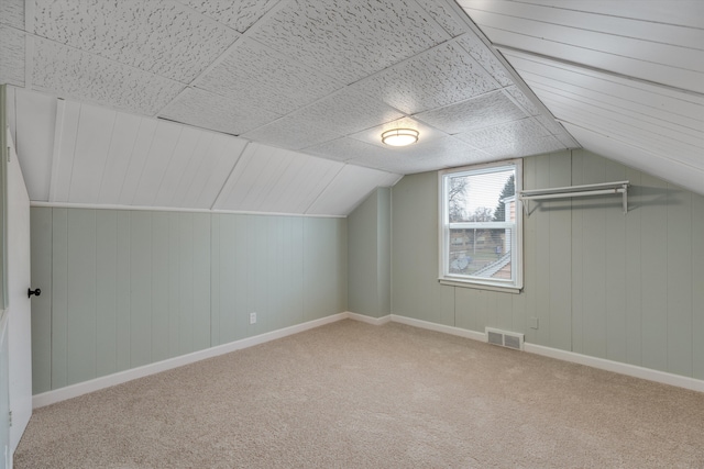 additional living space featuring wood walls, carpet, and lofted ceiling