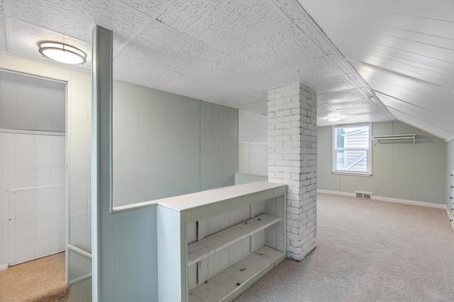 bonus room with light carpet, wood walls, and lofted ceiling