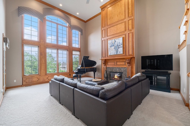 living room featuring a towering ceiling, a premium fireplace, a wealth of natural light, and light colored carpet