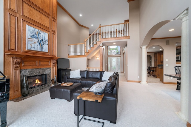 carpeted living room with a high ceiling, a fireplace, and ornamental molding