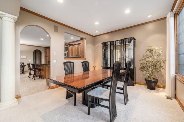 dining space with ornamental molding, light colored carpet, and ornate columns