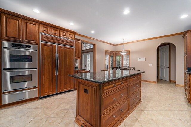 kitchen featuring a center island, decorative light fixtures, paneled built in refrigerator, double oven, and dark stone counters