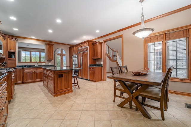 kitchen featuring hanging light fixtures, a center island, crown molding, and dark stone countertops