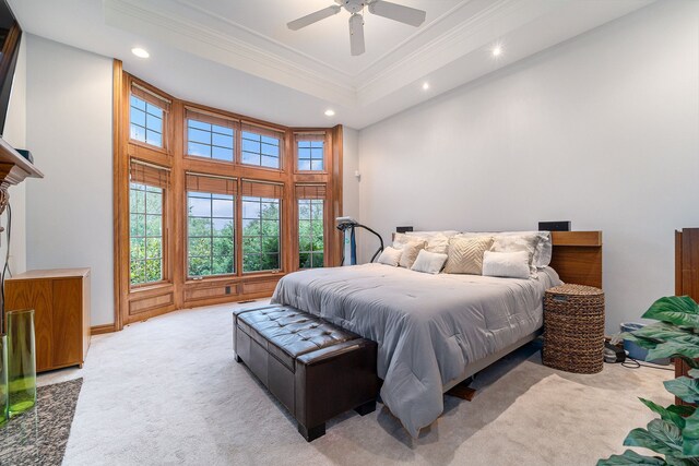 carpeted bedroom with ceiling fan, ornamental molding, a high ceiling, and a tray ceiling