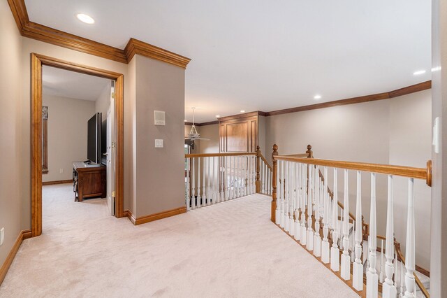 hallway with ornamental molding and light colored carpet