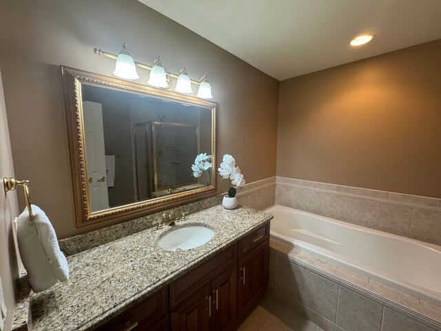 bathroom with tile patterned flooring, independent shower and bath, and vanity