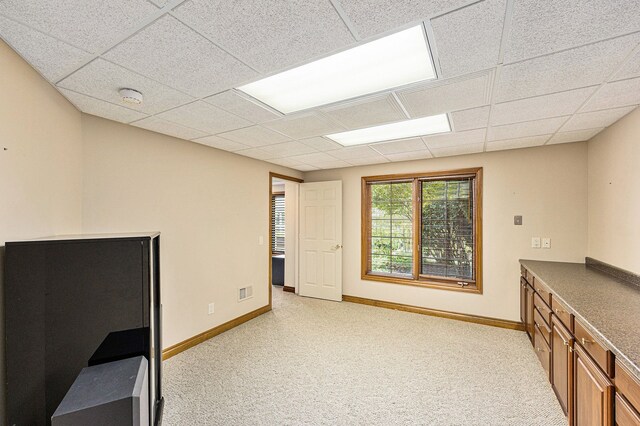 carpeted office space featuring a paneled ceiling