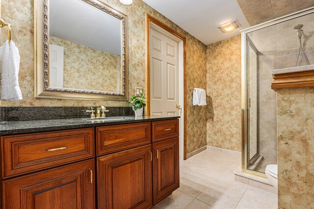 bathroom featuring a shower with door, tile patterned floors, vanity, and toilet