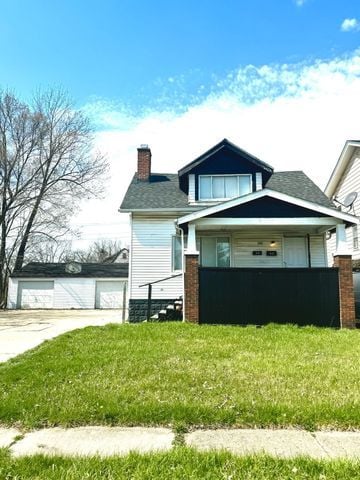 view of side of property featuring a garage, a lawn, and an outdoor structure