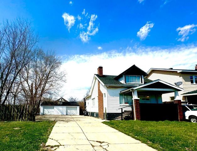 view of front of property with a garage, a front lawn, and an outdoor structure