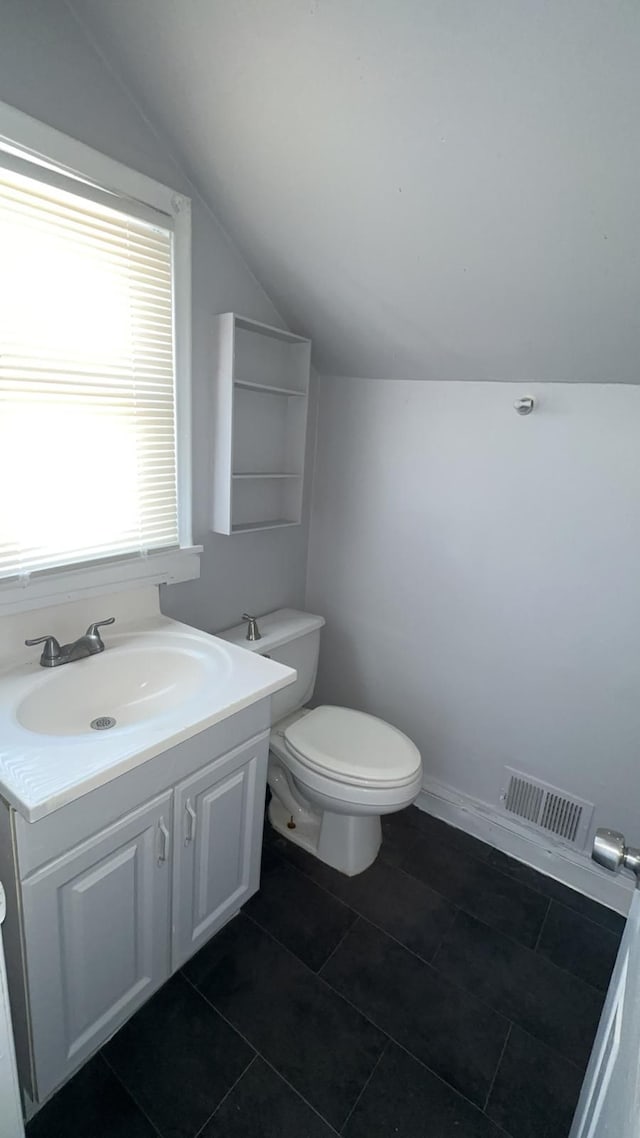 bathroom featuring tile patterned floors, toilet, vanity, and vaulted ceiling