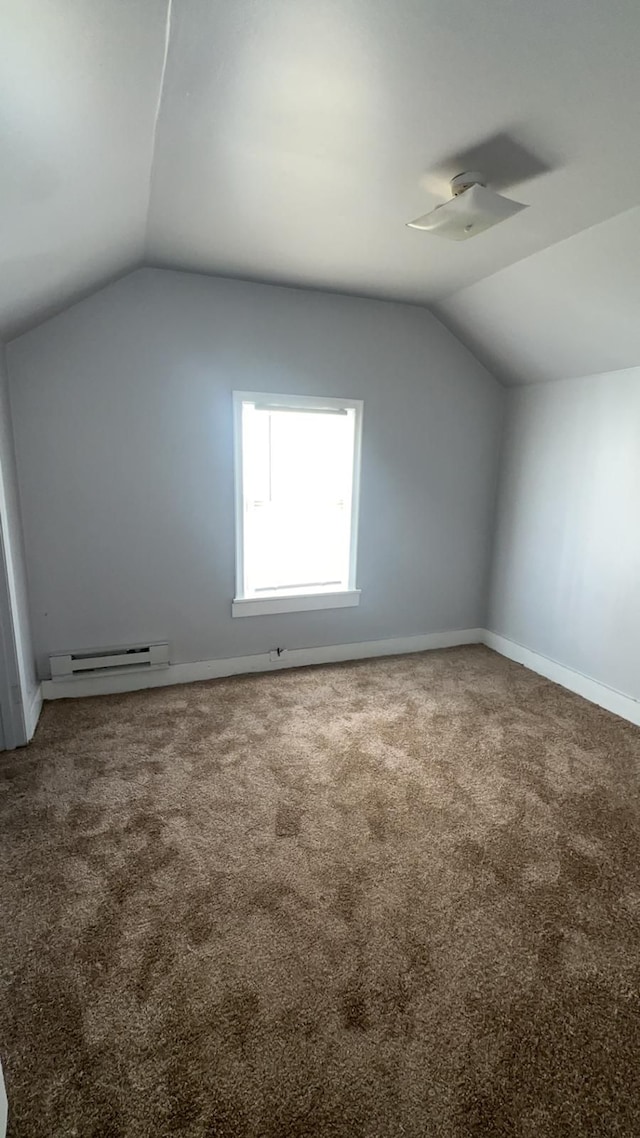 additional living space with a baseboard radiator, carpet flooring, and vaulted ceiling