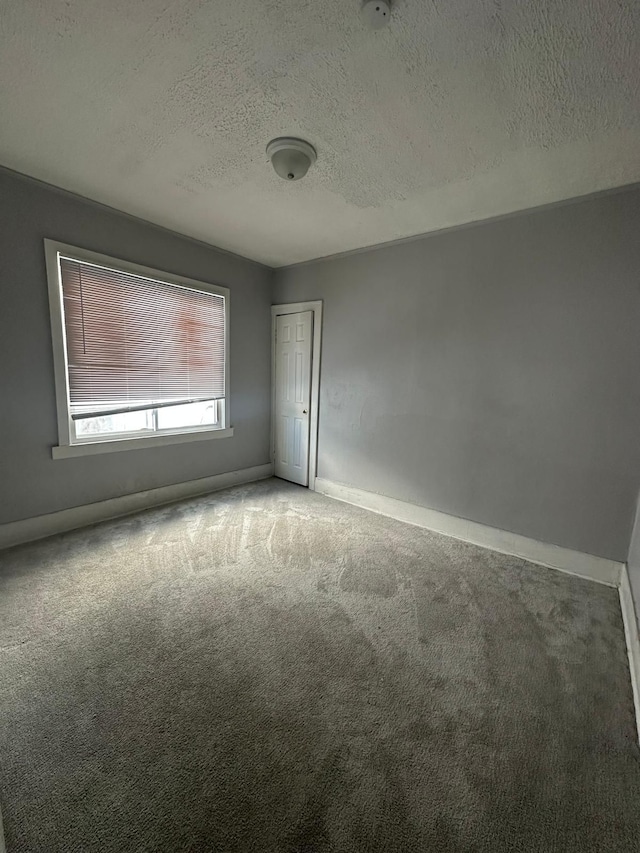 carpeted empty room featuring a textured ceiling