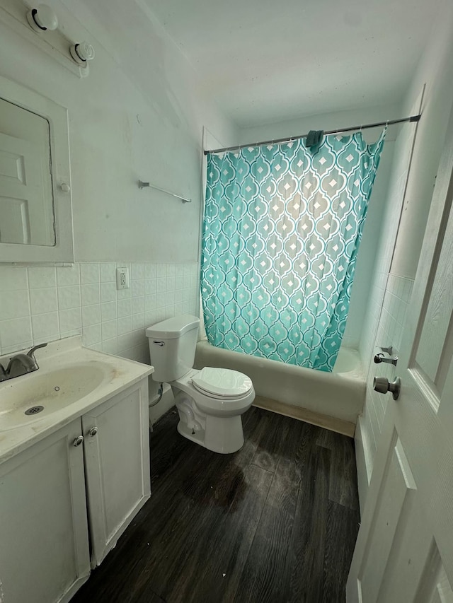 full bathroom with tile walls, hardwood / wood-style floors, toilet, vanity, and shower / bath combo with shower curtain