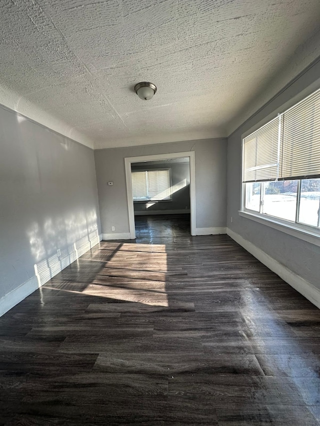 empty room with dark wood-type flooring and a textured ceiling