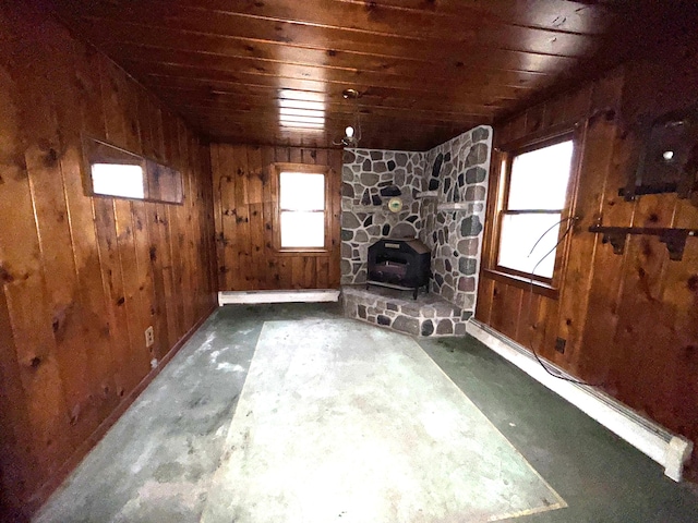 unfurnished living room featuring wood walls, a wood stove, and wooden ceiling