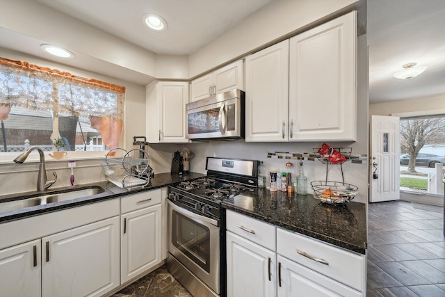 kitchen featuring dark stone countertops, sink, white cabinets, and appliances with stainless steel finishes