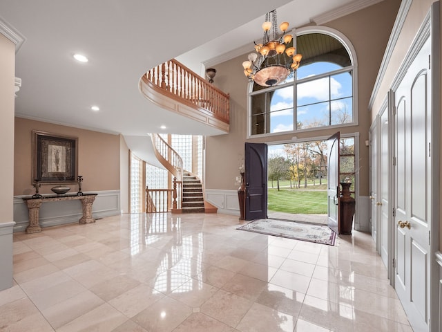 foyer entrance with ornamental molding, light tile patterned floors, and an inviting chandelier