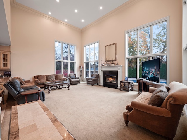 carpeted living room featuring a healthy amount of sunlight, a towering ceiling, and ornamental molding