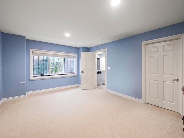 unfurnished bedroom with ensuite bathroom and light colored carpet