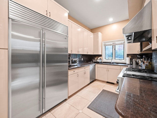 kitchen featuring backsplash, stainless steel appliances, sink, light tile patterned floors, and range hood