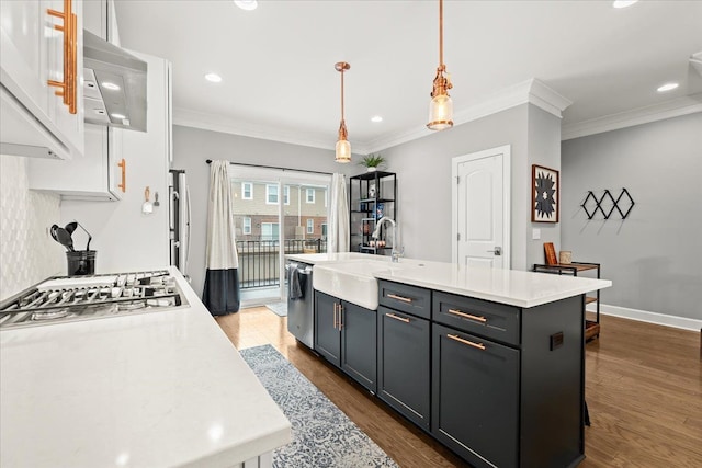 kitchen featuring decorative light fixtures, a center island with sink, appliances with stainless steel finishes, and dark hardwood / wood-style flooring