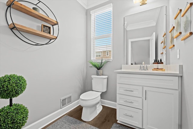 bathroom with toilet, vanity, ornamental molding, and hardwood / wood-style floors