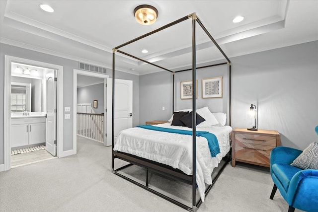 bedroom featuring ensuite bath, a tray ceiling, ornamental molding, light carpet, and sink