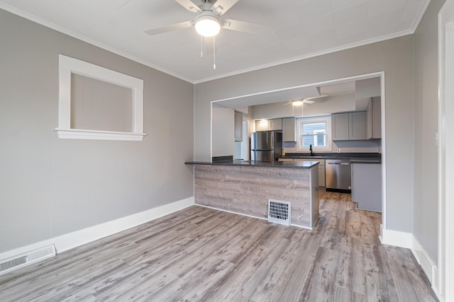 kitchen featuring light wood-type flooring, gray cabinetry, stainless steel appliances, ceiling fan, and crown molding