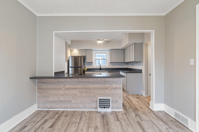 kitchen with stainless steel refrigerator, kitchen peninsula, gray cabinets, and light hardwood / wood-style floors