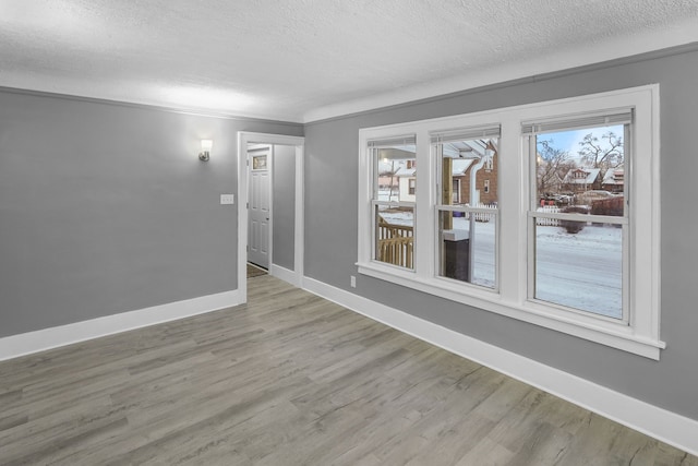 unfurnished room with light hardwood / wood-style floors, a textured ceiling, and ornamental molding