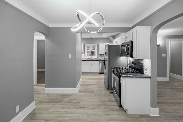 kitchen with white cabinets, decorative light fixtures, appliances with stainless steel finishes, and tasteful backsplash