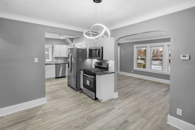 kitchen featuring tasteful backsplash, white cabinetry, light hardwood / wood-style flooring, pendant lighting, and stainless steel appliances