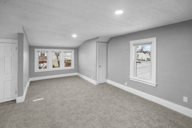 bonus room with carpet flooring, a textured ceiling, and lofted ceiling