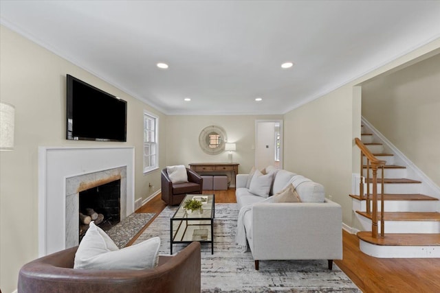 living room with light hardwood / wood-style flooring, ornamental molding, and a tiled fireplace