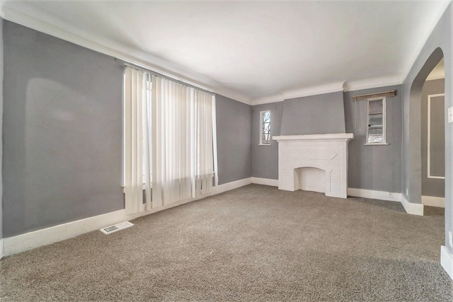 unfurnished living room featuring carpet flooring, ornamental molding, and a fireplace