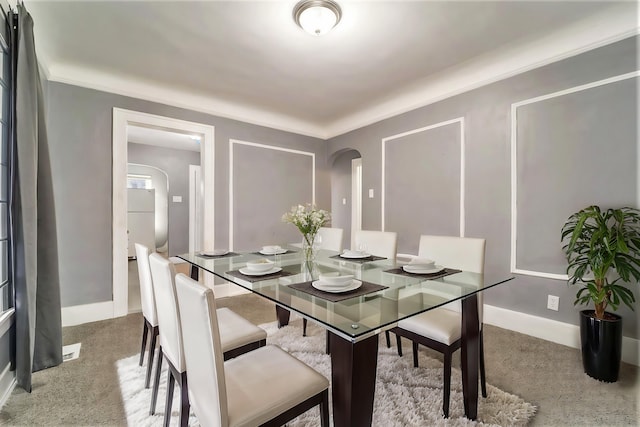 carpeted dining room with crown molding